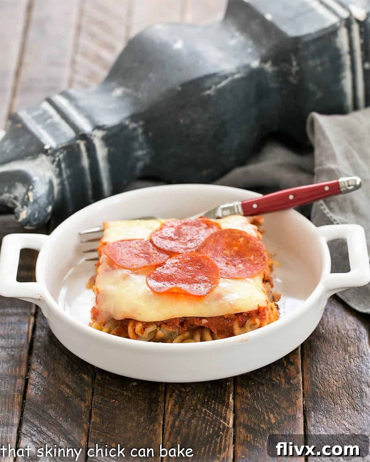 A close-up side view of the bubbling, cheesy Easy Pizza Bake in a small white casserole dish, ready to be served.