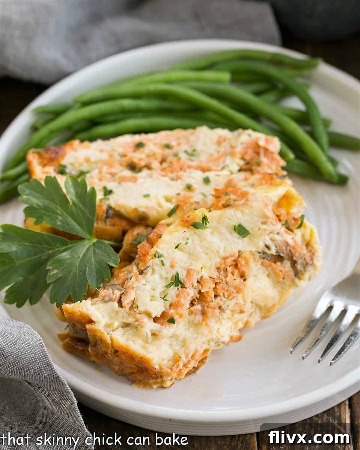 Two slices of golden-brown baked salmon loaf, perfectly plated with a side of vibrant green beans, ready to be enjoyed.