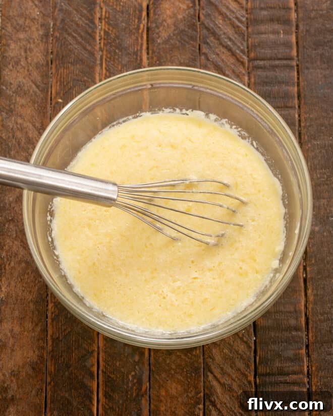 Step 2: Melted butter, milk, and salt being added to the whisked eggs, ready to be combined.