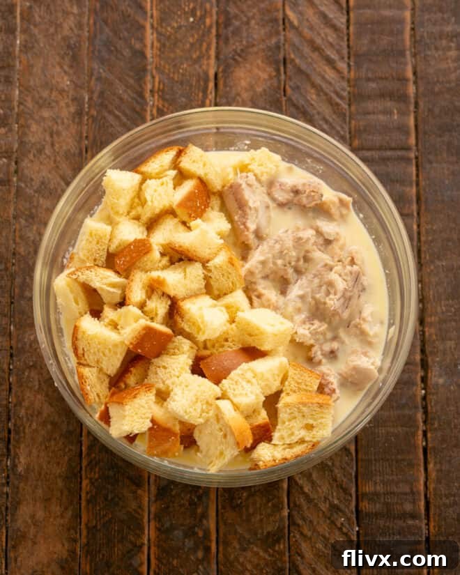 Step 3: Cubed soft bread and flaked canned salmon gently tossed together in a bowl with the liquid mixture.