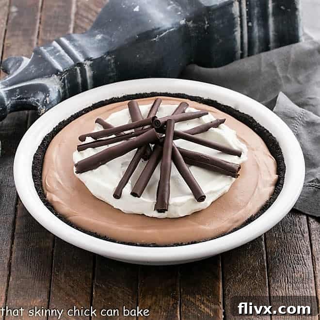 Chocolate pie in a white pie plate topped with whipped cream and chocolate curls