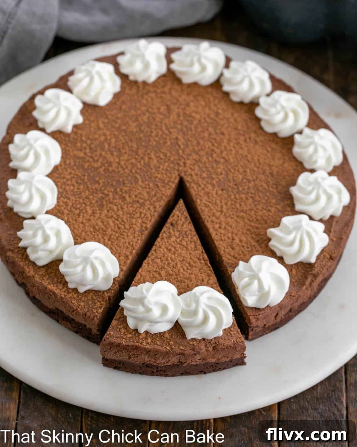 Overhead view of a beautifully presented chocolate ganache cake with one slice expertly cut, revealing its moist interior and airy topping.