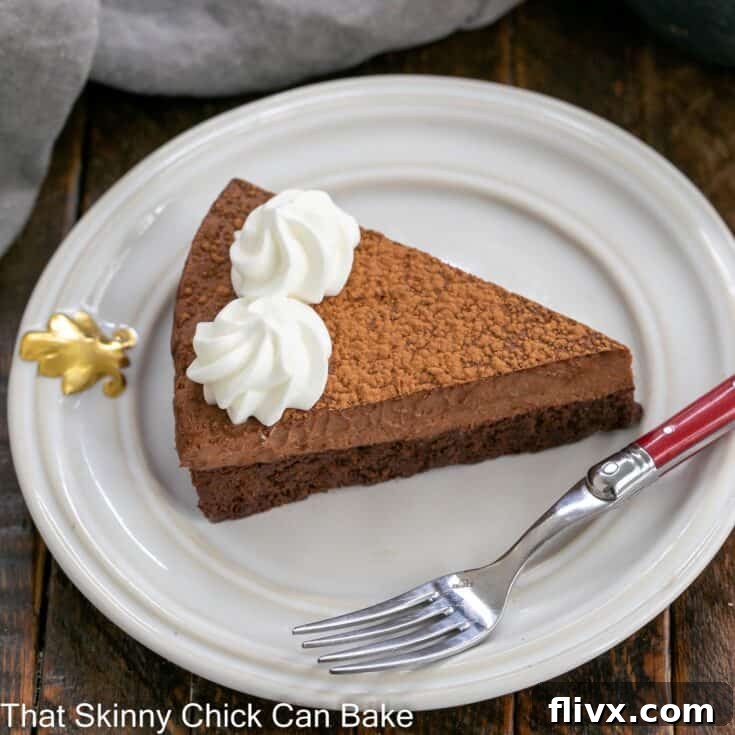 A delectable slice of whipped chocolate-topped chocolate cake, elegantly plated with a red-handled fork, ready to be enjoyed.