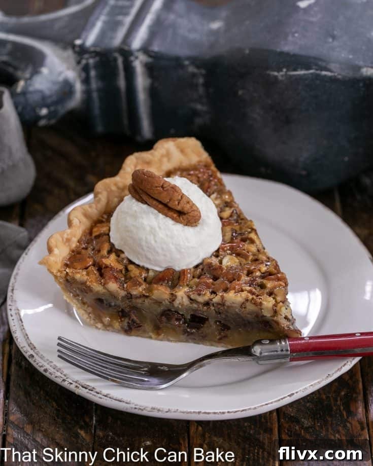 Slice of chocolate pecan pie on a dessert plate topped with whipped cream and a pecan