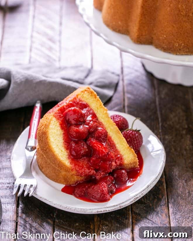 Slice of lemon bundt cake on a white plate with the cake stand in the background