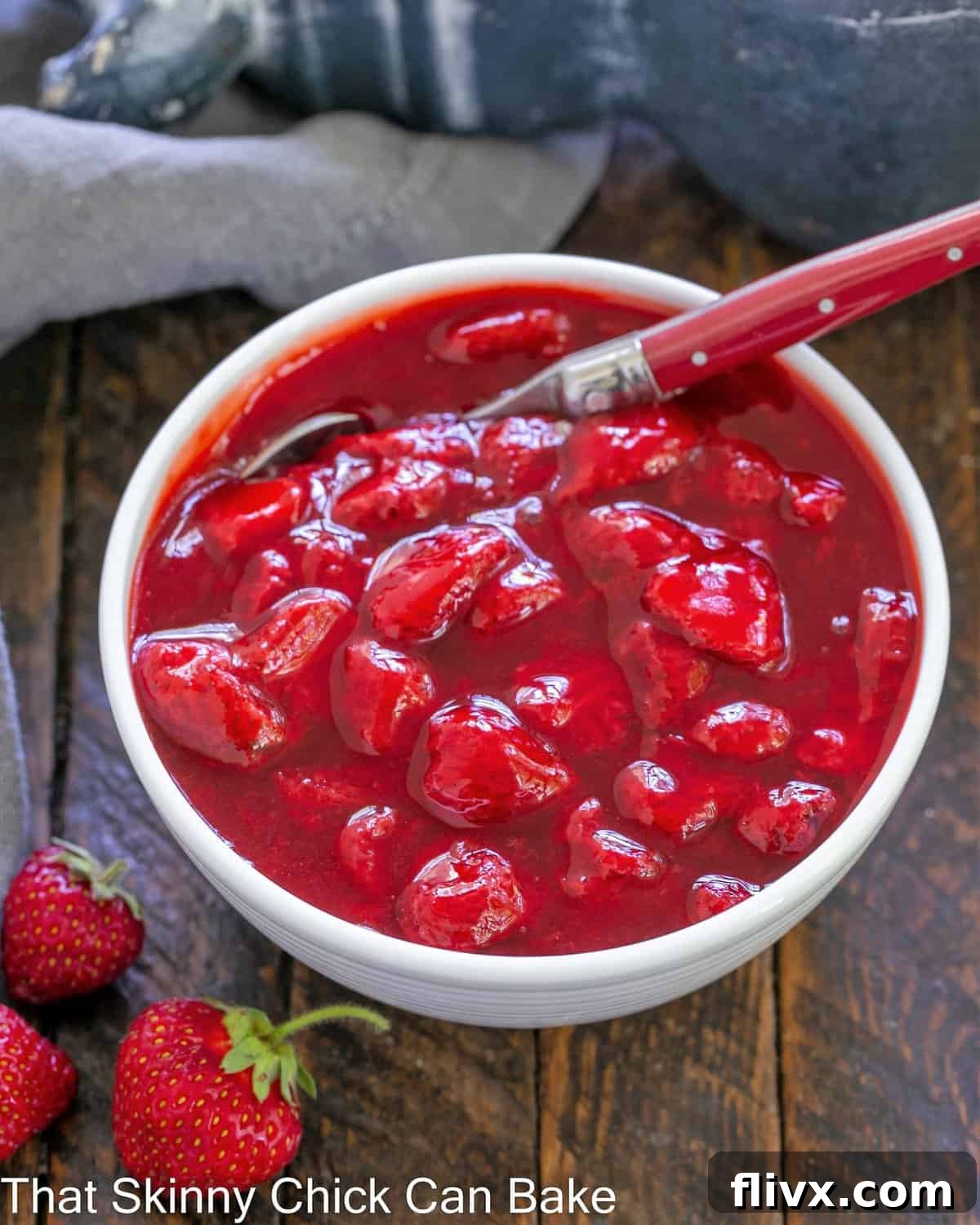 Overhead view of homemade fresh strawberry compote in a white bowl with a spoon, ready to serve.