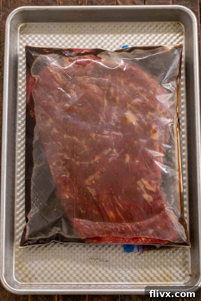 Process shot 1: Flank steak being added to marinade in a Ziploc bag for chilling.