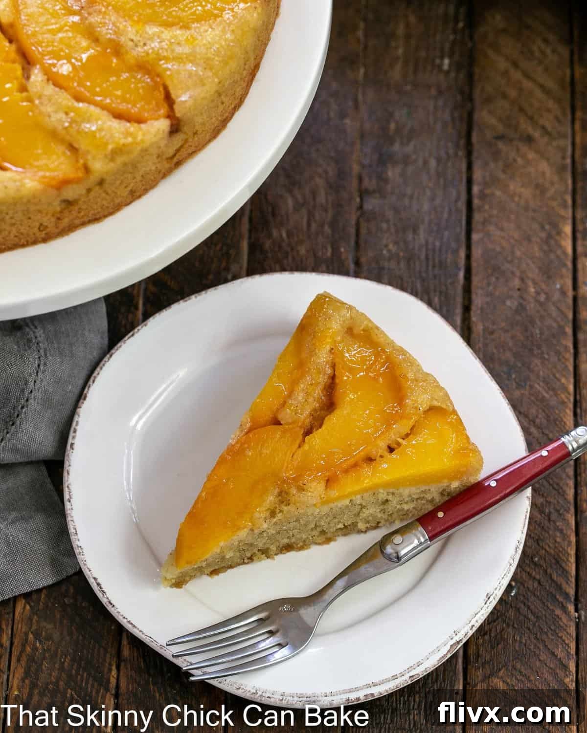 A slice of upside down cake with peaches on a white plate viewed from above.