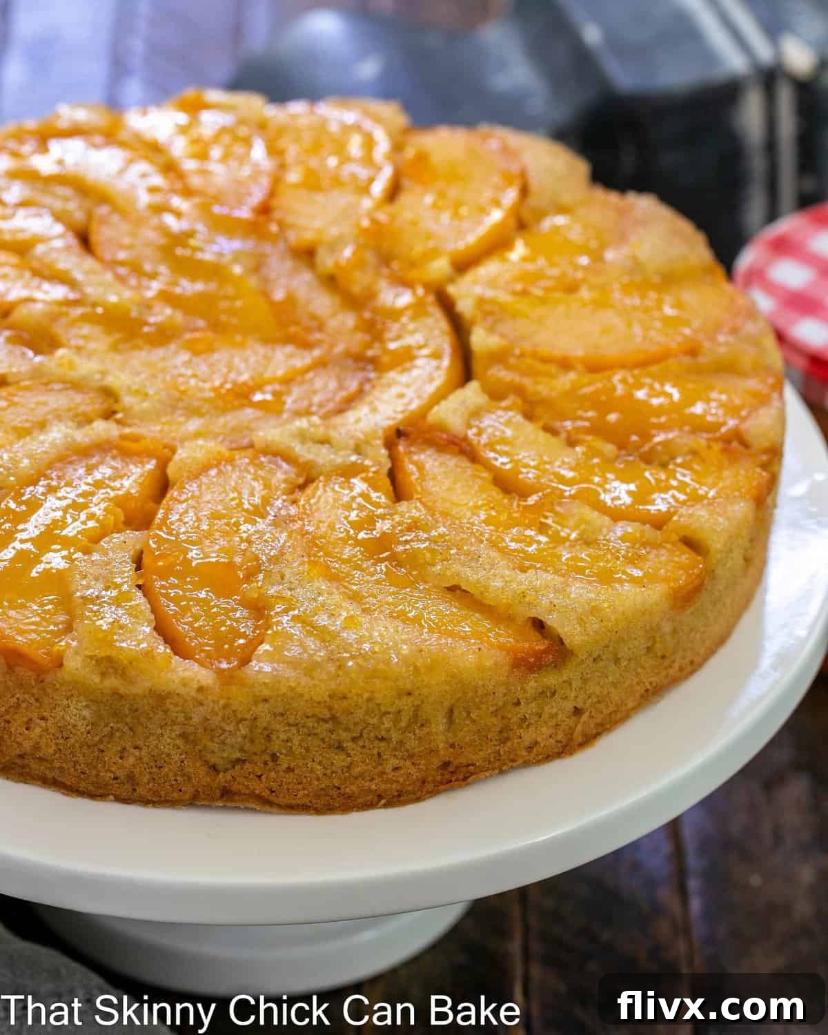 Peach upside down cake on a white ceramic cake stand.