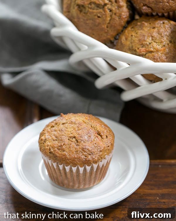 A generous display of warm Buttermilk Bran Muffins in a white basket, with a single muffin enticingly placed in the foreground, highlighting its inviting texture.