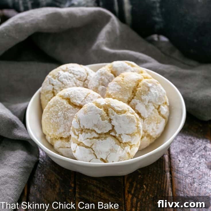 Five gooey butter cake cookies presented in a small white ceramic bowl, showcasing their golden hue and inviting crackled tops.