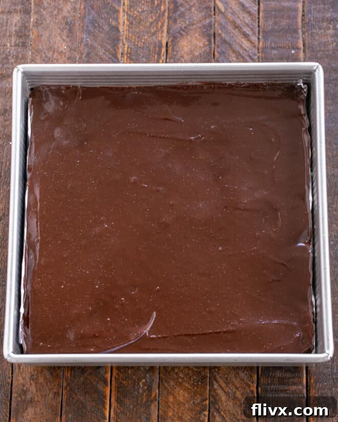 Brownie batter being poured and spread over the Oreo layer.