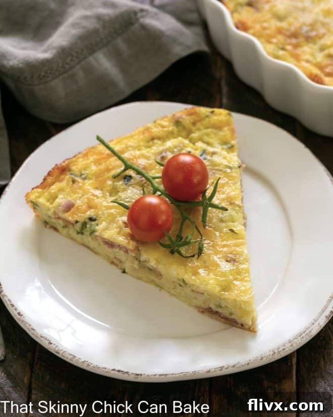 Slice of Zucchini Quiche with Prosciutto garnished with cherry tomatoes on a white plate