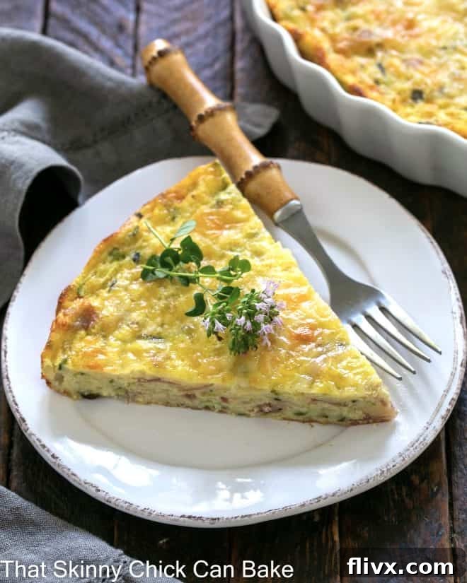 Slice of zucchini quiche garnished with a thyme sprig on a white plate with a bamboo fork.