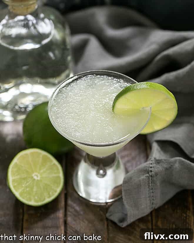 Easy 3-Ingredient Beer Margaritas with a lime garnish and tequila and limes in the background.