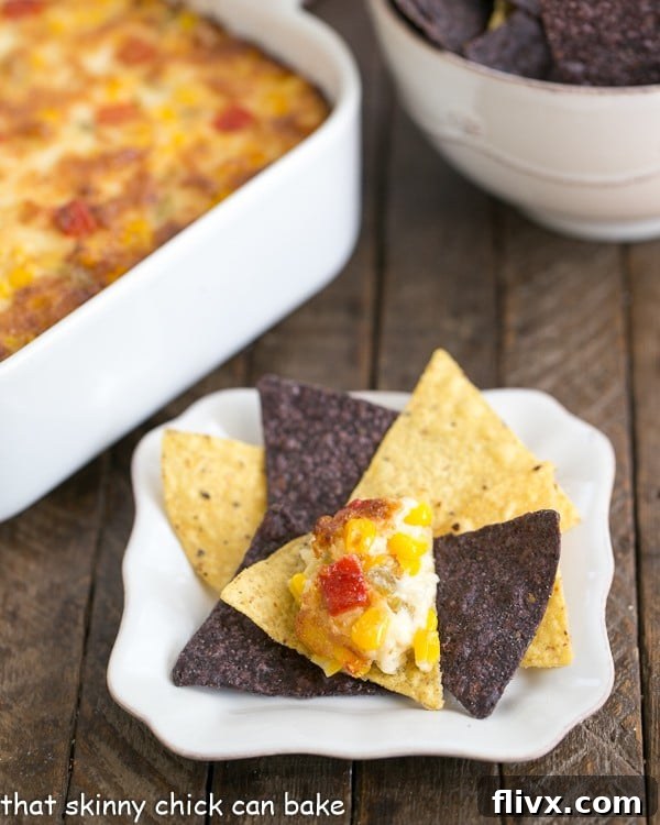 A close-up shot of creamy Fiesta Corn Dip on a crispy tortilla chip, ready to be enjoyed. The dip is golden brown with visible corn kernels and melted cheese.