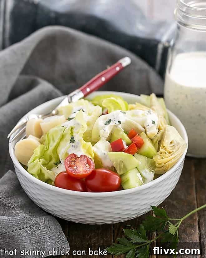 The Ultimate Homemade Ranch Dressing - Fresh herbs and wholesome ingredients create the perfect salad topping. A creamy, homemade ranch dressing in a white ceramic bowl, ready to be served with a red-handled fork.