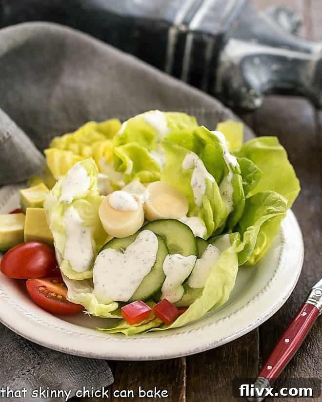 Homemade Ranch Dressing - Made with fresh herbs and wholesome ingredients, the perfect salad topping. A vibrant salad dressed with the ultimate homemade ranch dressing, served on a round white plate.