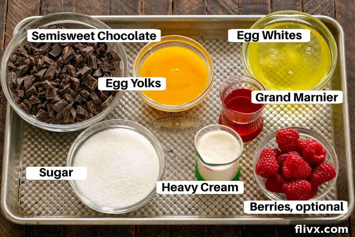 Essential ingredients for French chocolate mousse, neatly arranged on a metal sheet pan, including eggs, sugar, chocolate, butter, coffee, and liqueur.