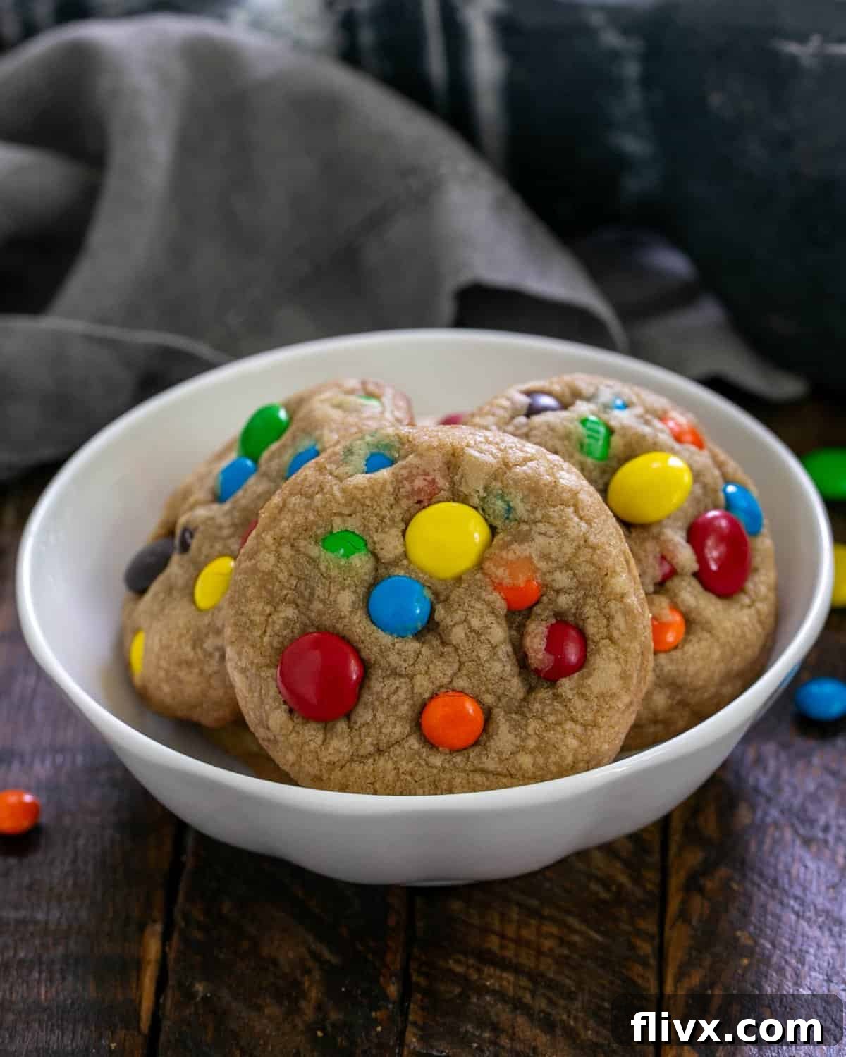 A small white bowl filled with freshly baked Brown Butter M&M Cookies, showcasing their appealing texture and colorful M&Ms.