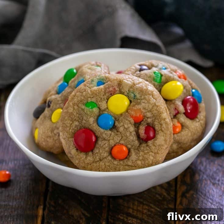 Brown butter M&M cookies in a shallow white bowl, showcasing their golden-brown color and abundant M&Ms.