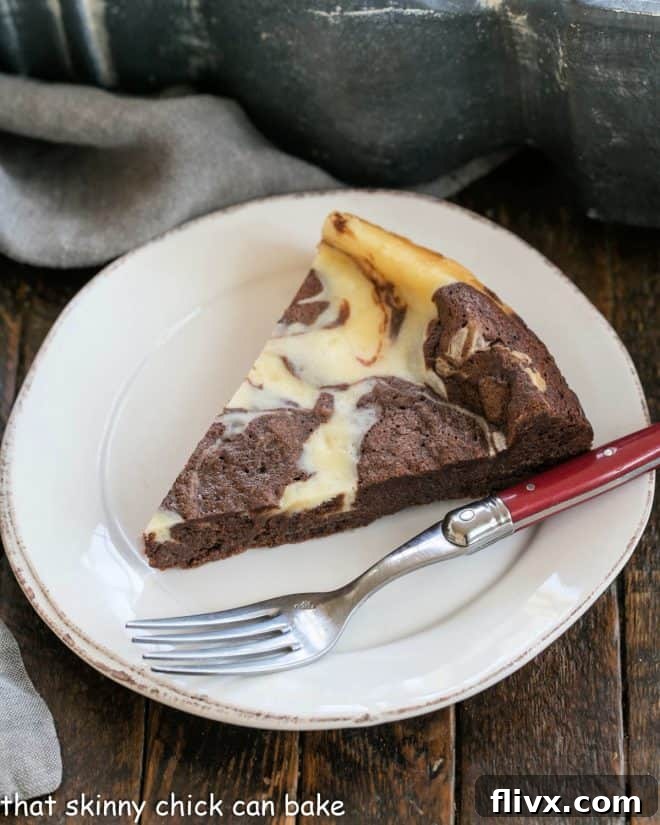 Overhead view of a perfectly sliced Marbled Flourless Chocolate Cake on a white dessert plate with a red-handled fork, highlighting the intricate vanilla and chocolate swirls and dense texture.