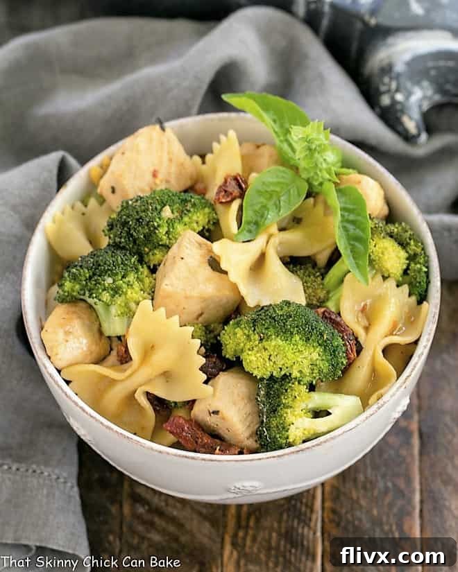 An inviting overhead view of a white ceramic bowl filled with Chicken with Broccoli, Sun-dried Tomatoes and Bow Tie Pasta, ready to be served and enjoyed, showcasing its vibrant colors and rich textures.