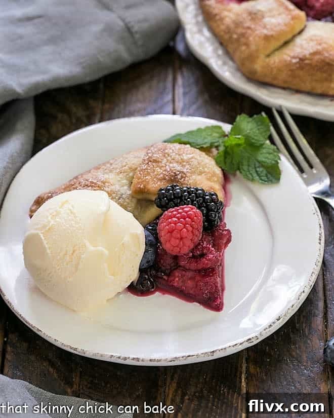 Mixed Berry Galette - a summer Fruit Tart made with sweet, seasonal berries Slice of berry galete on a round white plate with a scoop of vanilla ice cream.