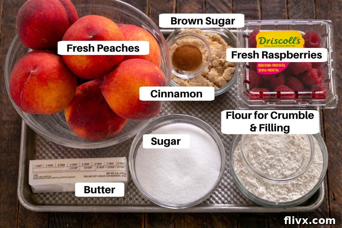 A flat lay photograph showcasing all the fresh ingredients for Peach Raspberry Crisp neatly arranged on a baking sheet with clear labels.