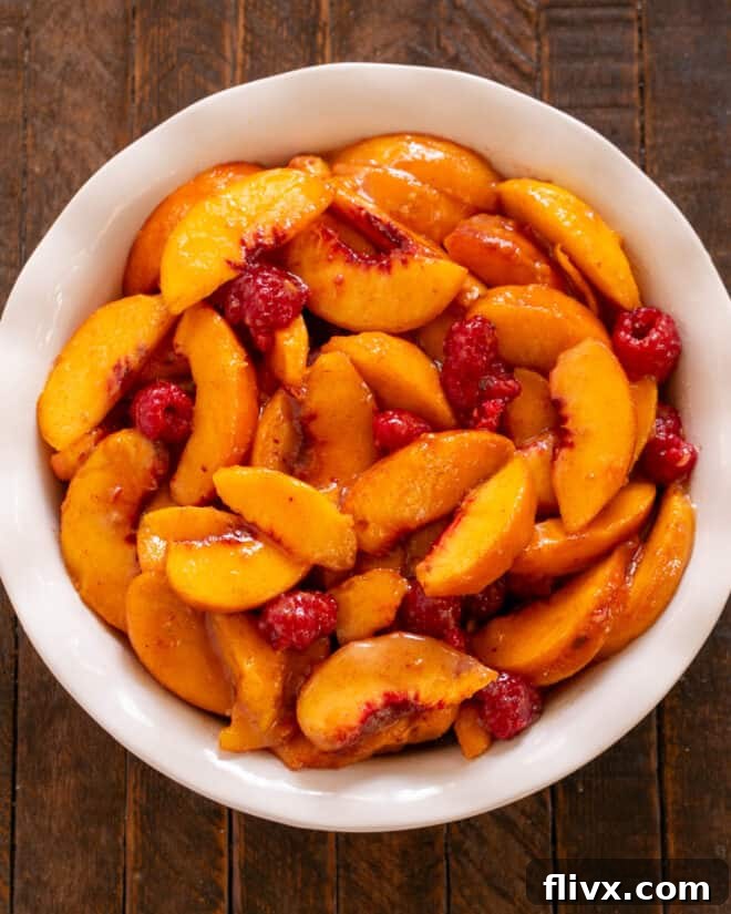 The fruit mixture evenly spread out in a ceramic baking dish, ready for the crumble topping.