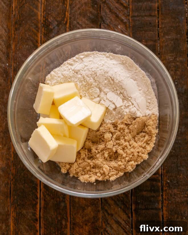 Close-up of butter, brown sugar, and flour being cut together in a bowl to form the crisp's topping crumbs.