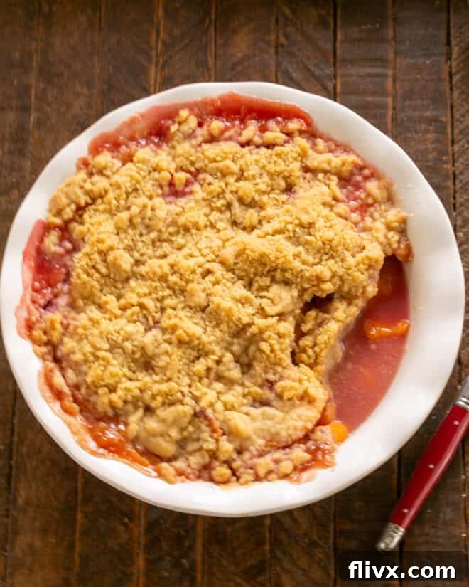 A golden-brown Peach Raspberry Crisp, fresh from the oven, with bubbly filling visible around the edges, ready to be served warm.