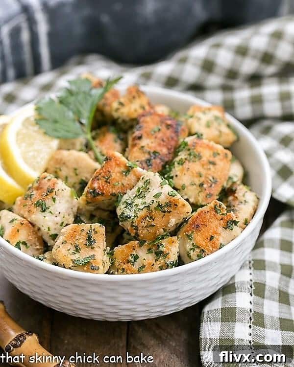 A white bowl filled with Pan-Fried Chicken with Garlic and Parsley, elegantly placed on a green and white checked napkin, suggesting a cozy and delicious meal setting.