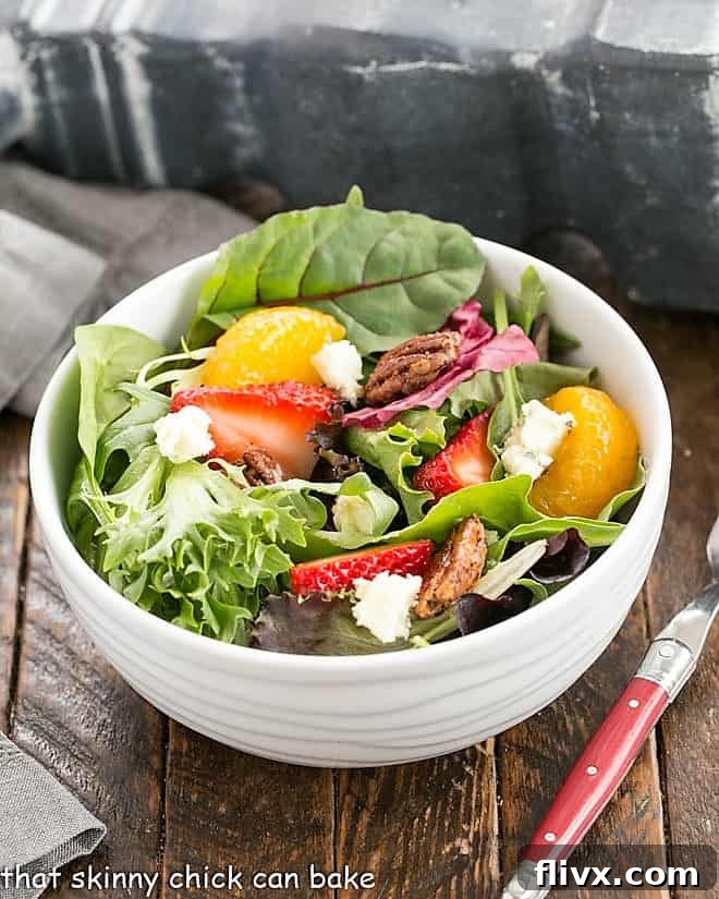 Overhead view of strawberry spinach salad in a white serving bowl, showcasing its colorful ingredients and inviting presentation.