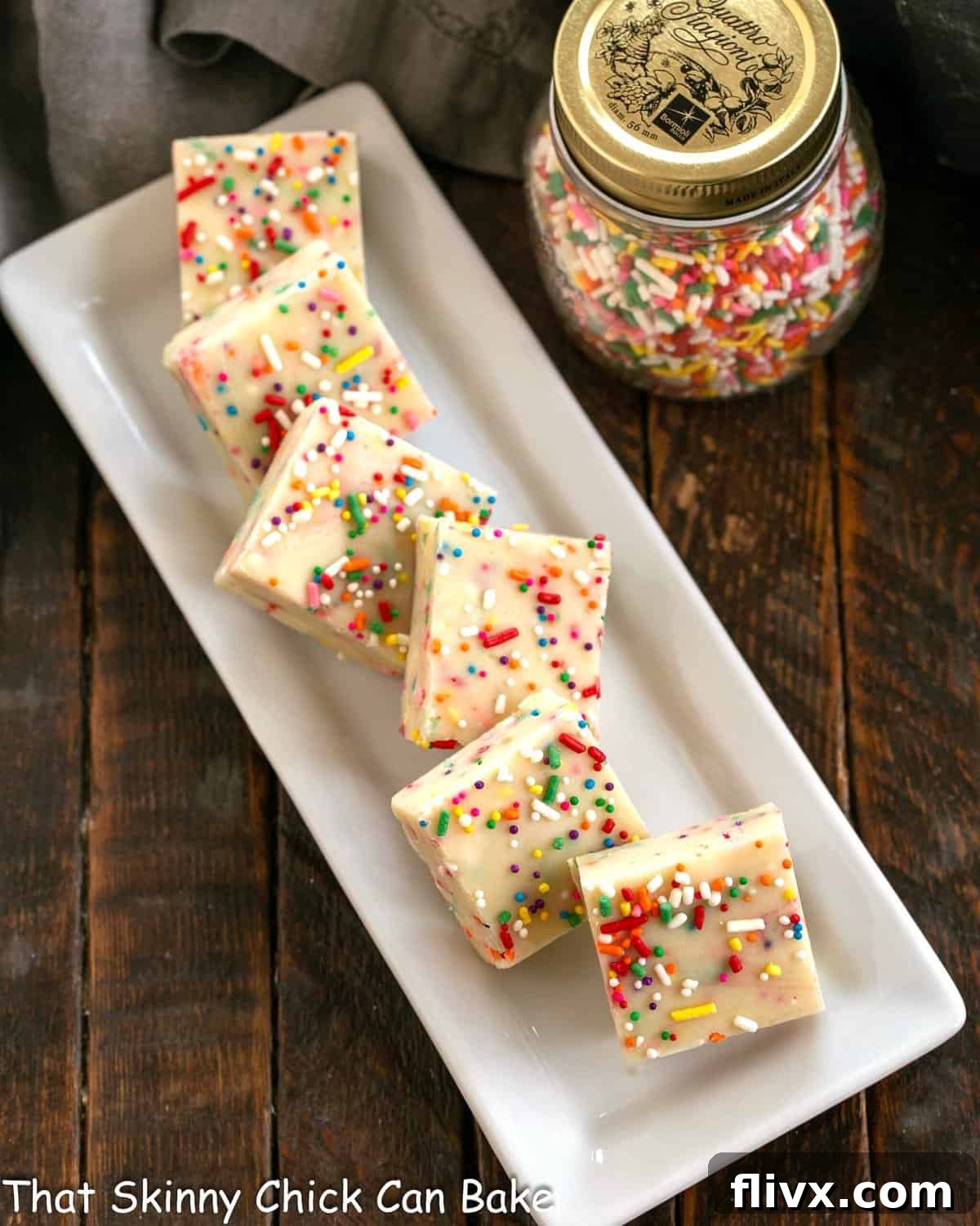 Squares of cake batter fudge on a white ceramic tray.