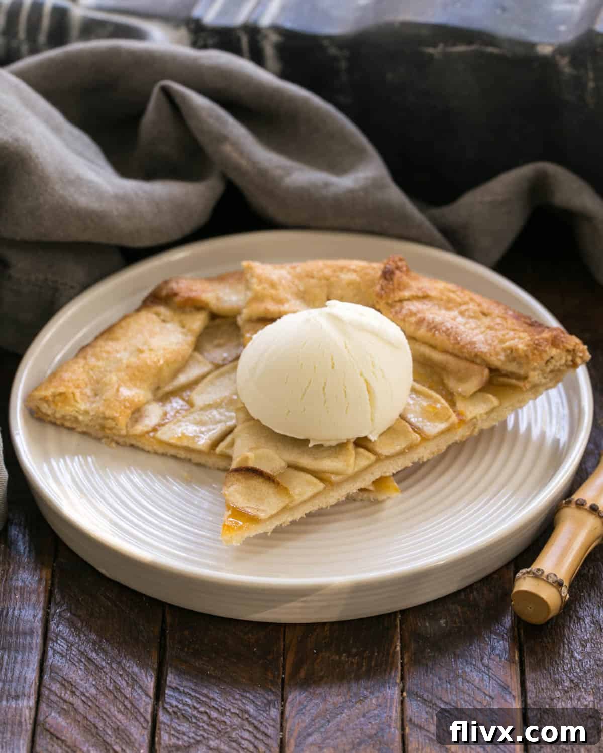 Two generous slices of Apple Tart, served on a pristine white plate, accompanied by a melting scoop of vanilla ice cream, ready to be enjoyed.