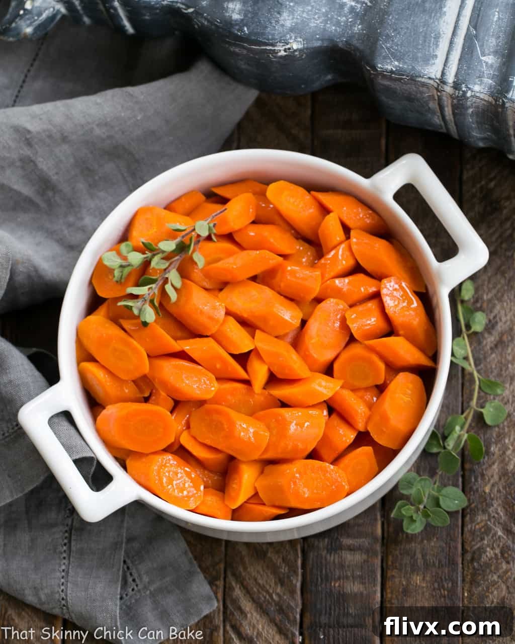 Bourbon Maple Glazed Carrots in a round ceramic dish garnished with fresh herbs.