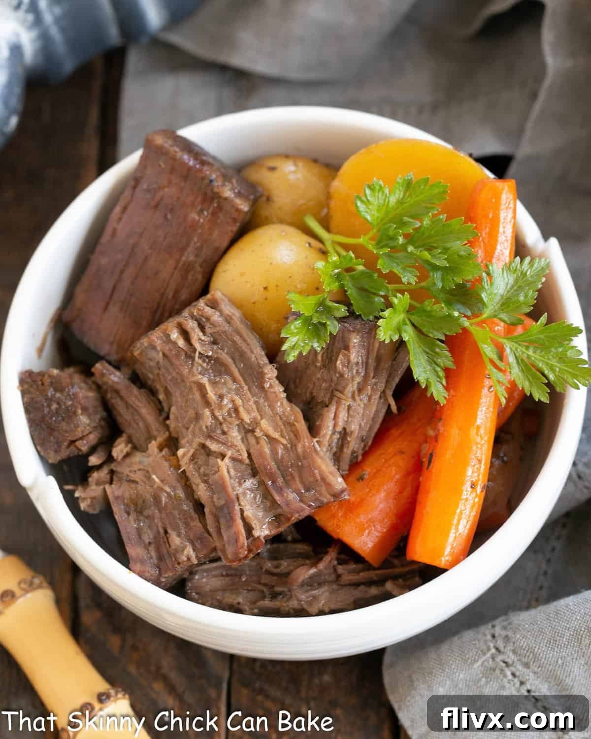 Beef Chuck Roast dished out into a white bowl with carrots and potatoes.