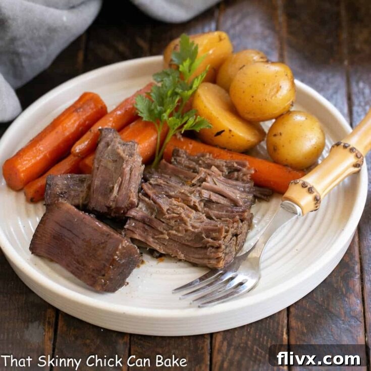 Beef chuck roast and vegetables on a white plate with a fork.