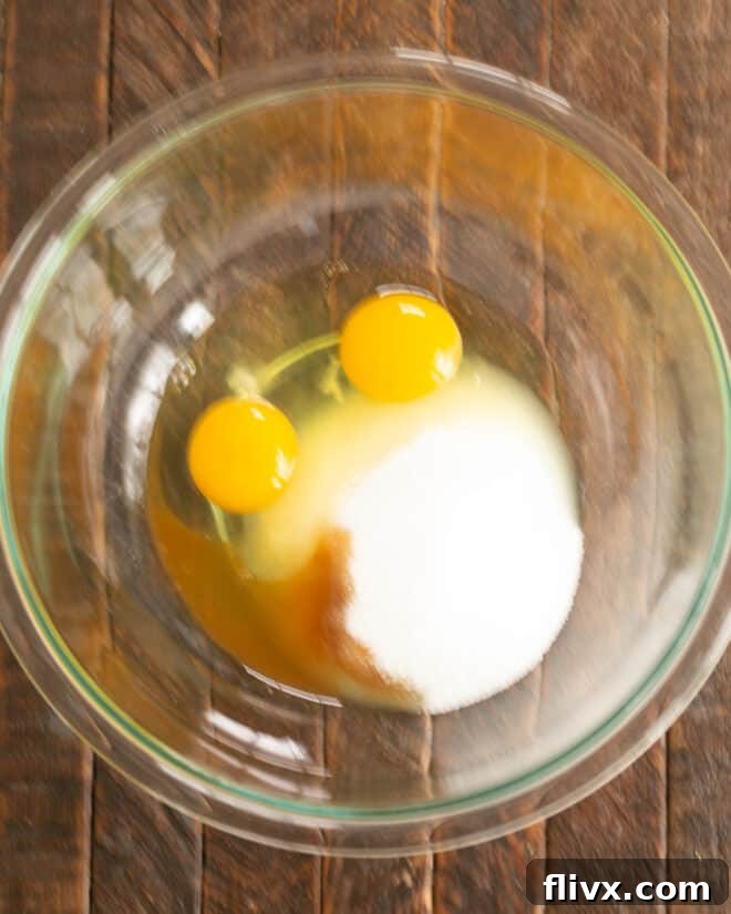 Step 2: Eggs, sugar, and vanilla extract are vigorously whisked in a separate bowl, creating a light and airy mixture.
