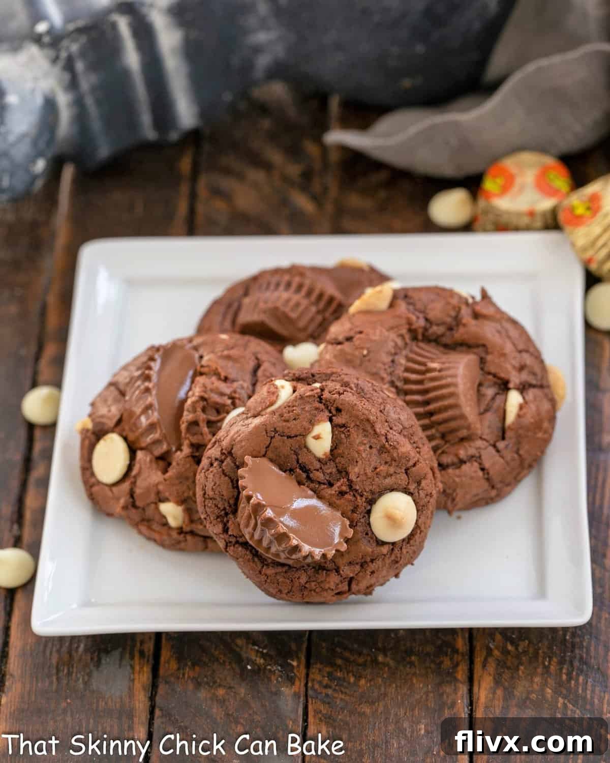 Four perfectly baked Moose Tracks Cookies are artfully arranged on a square white ceramic plate, showcasing their rich texture and abundant fillings.