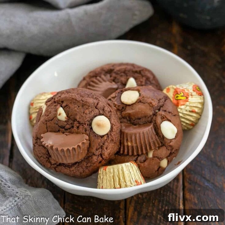 Moose Tracks Cookies are presented in a pristine white ceramic bowl, showcasing their rich chocolate color and generous chunks of peanut butter cups and white chocolate chips.