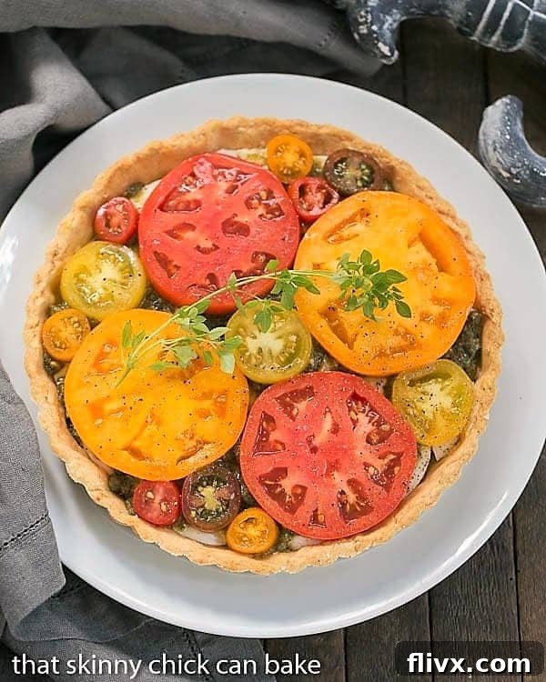 Overhead view of a Fresh Tomato Tart on a serving plate garnished with fresh basil leaves, highlighting its colorful presentation.