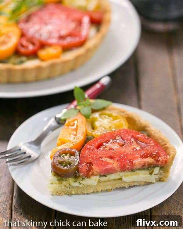 Slice of Fresh Tomato Tart on a small white plate with a red handled fork, showing the layers of cheese and tomato.