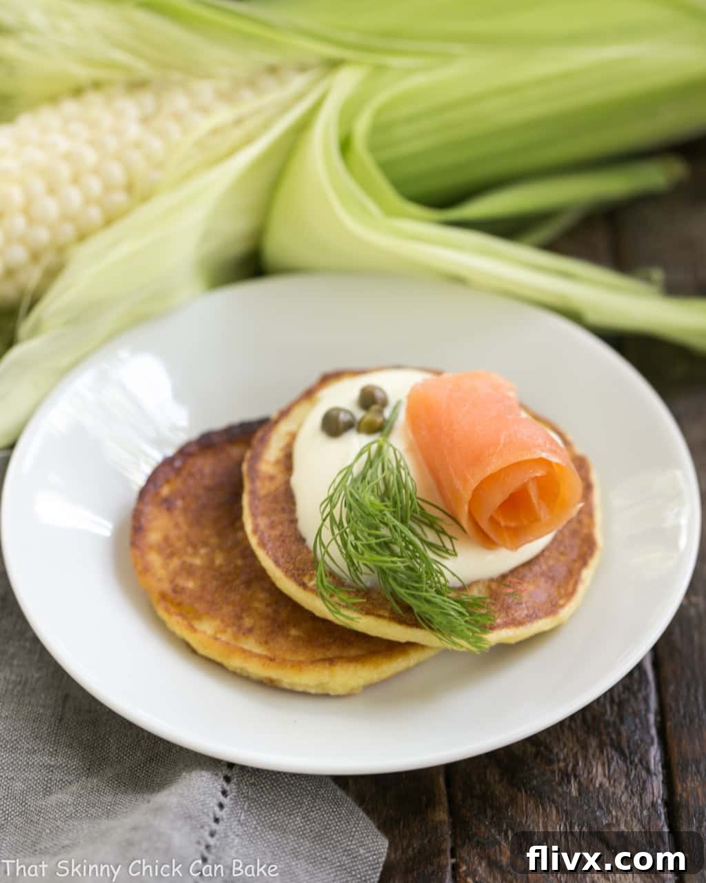 Savory Corn Cakes on a round white plate with toppings like smoked salmon, creme fraiche, and dill.
