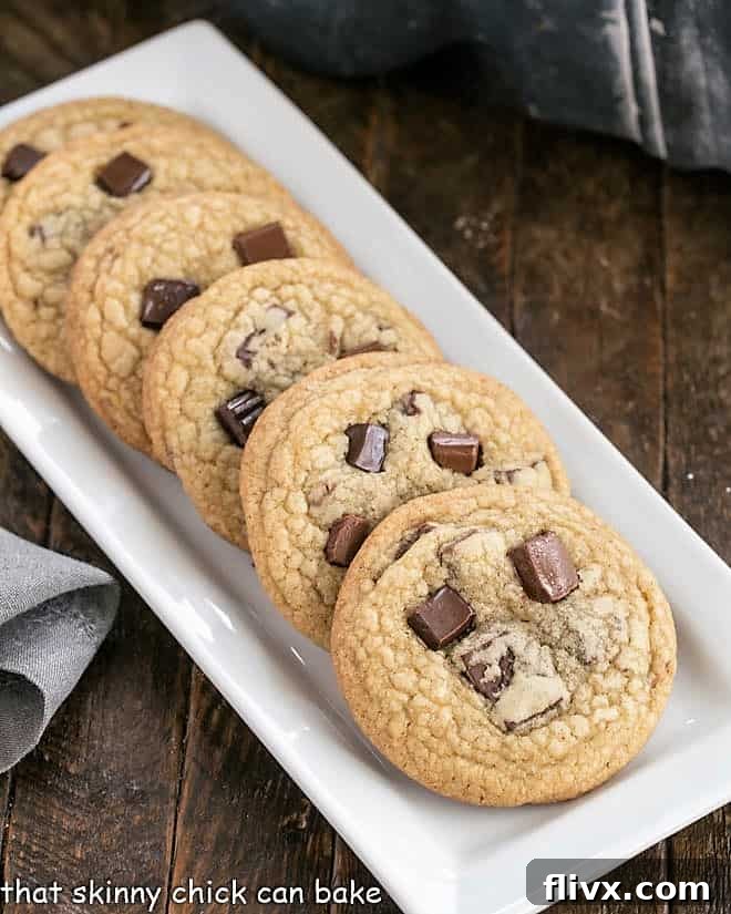 A lineup of rich, chewy Dark Brown Sugar Chocolate Chunk Cookies on a narrow white serving tray, highlighting their perfect golden-brown edges and molten chocolate centers.