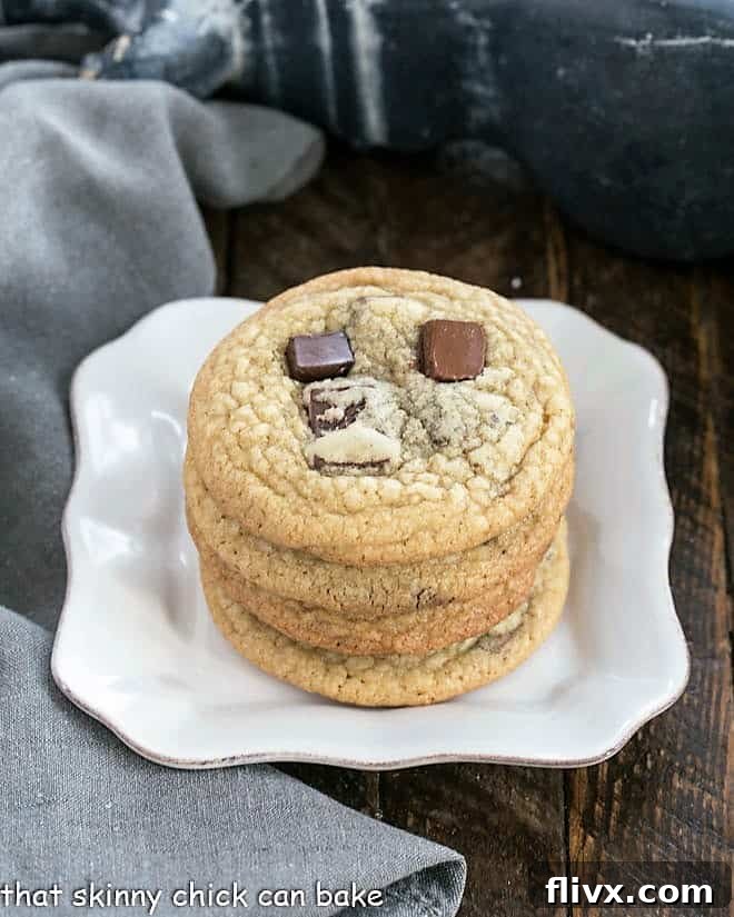 A stack of golden-brown Dark Brown Sugar Chocolate Chunk Cookies on a square white plate, glistening with melted chocolate.