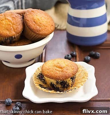 Sour Cream Blueberry Muffins - Moist, tender and full of berries! Sour Cream Blueberry Muffins on a white ceramic plate with the paper wrapper removed