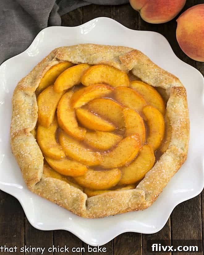 Overhead view of a beautifully golden-brown Rustic Peach Galette on a ruffled white serving plate, showcasing its golden crust and juicy peach filling.