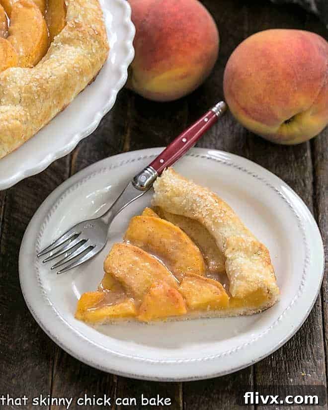 Step 8: A slice of the baked peach galette, revealing its golden crust and tender fruit, rests on a white plate with a red-handled fork, ready to be enjoyed.